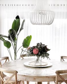 a dining room table with flowers and greenery on it