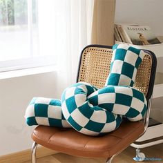 a green and white checkered pillow sitting on top of a chair next to a window