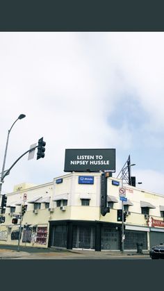 a street corner with a traffic light and building on the corner that says listen to nippery hussel