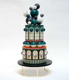 a multi - tiered cake is decorated with black, white and green decorations on top