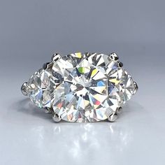 three stone diamond ring on grey background with reflection in the middle and side stones visible