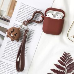 an apple airpods case with a keychain attached to it, sitting on top of a book