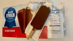 an ice cream and chocolate popsicle are on the counter next to a package of blue ribbon