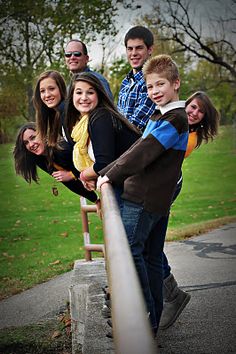 a group of people standing next to each other on a sidewalk near grass and trees