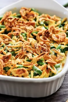 a casserole dish filled with green beans and fried onion flakes on a wooden table