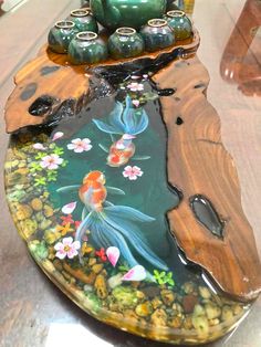 a glass table topped with a fish pond and vases on top of each other