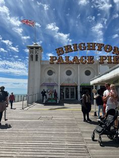 people are standing in front of the brighton palace pier on a sunny day with blue skies and white clouds