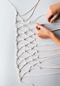 two hands are working on a string art piece