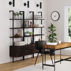 a room with a table, chair and bookshelf next to a clock on the wall