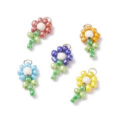 four different colored beaded flower charms on a white background with clippings attached to them