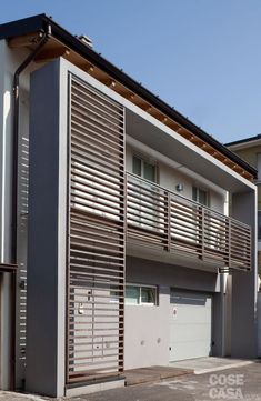 an apartment building with shutters on the front and garage doors open to let in light