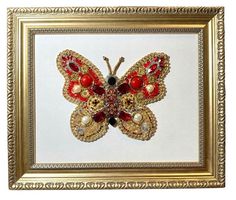 a gold frame with a red and black butterfly in it's center, hanging on the wall