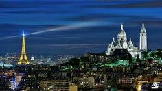 the city skyline is lit up at night with lights in the buildings and spires