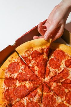 a person is cutting into a pepperoni pizza