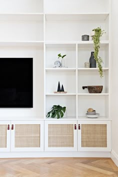 an entertainment center with white shelves and wicker baskets