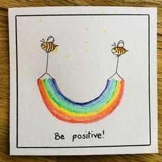 a card with two bees flying over a rainbow and the words be positive on it