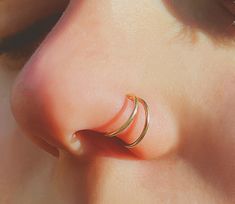 a woman's nose with two gold rings on it