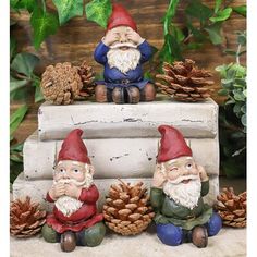 three gnome figurines sitting next to pine cones