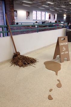 a broom is laying on the floor next to a caution sign