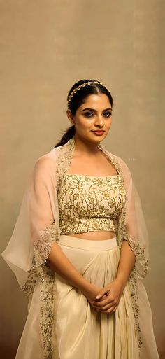 a woman in a white and gold outfit posing for the camera with her hands on her hips