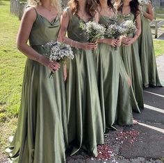 a group of women standing next to each other wearing green dresses and holding bouquets