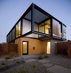 a modern house that is on the side of a fenced in area at dusk