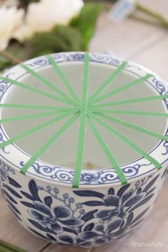 a blue and white bowl with green sticks sticking out of the top, sitting on a wooden table