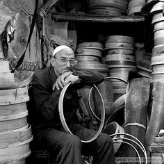 an old man sitting in the back of a truck with lots of tires on it