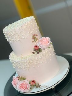 two tiered wedding cake with pink roses on the side and pearls on the top