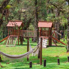 children's play area with swings and hammocks in the park, surrounded by trees