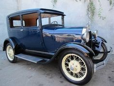 an old blue car parked in front of a building