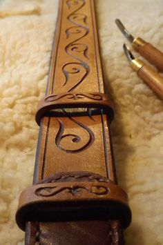 a pen and some pens sitting on top of a white rug next to a brown leather belt