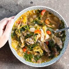 a person holding a spoon in a bowl of soup