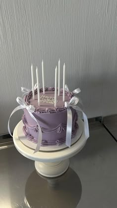 a purple cake with white candles on top