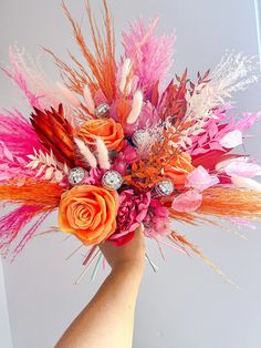 a woman's hand holding a bouquet of flowers and feathers