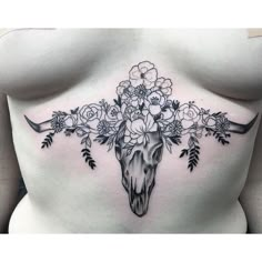 a woman's stomach with flowers and a cow skull on it