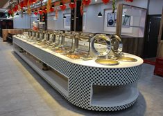 a long counter with lots of plates and bowls on it in a room that has red lanterns hanging from the ceiling