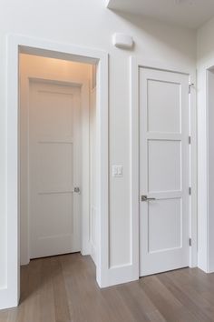 an empty room with white doors and hard wood floors