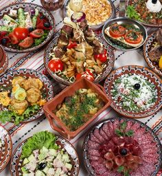 a table topped with lots of different types of plates and bowls filled with salads