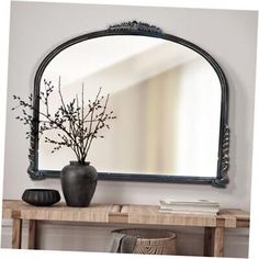 a mirror sitting on top of a wooden table next to a vase filled with flowers