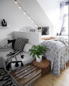 a bed room with a neatly made bed and a plant on the end table next to it