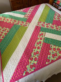 a bed with a pink and green quilt on it