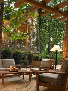 an outdoor living area with wooden furniture and candles on the table in front of it