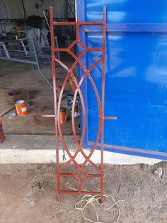 an old rusted iron door frame in front of a blue building with construction tools on the ground