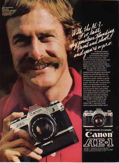 a man with a moustache holding an old camera