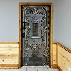 an ornate door in the corner of a room with tile flooring and wooden walls