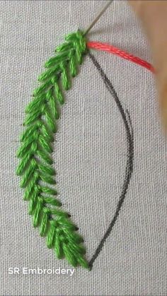 a close up of a piece of yarn with green leaves on it and a red string