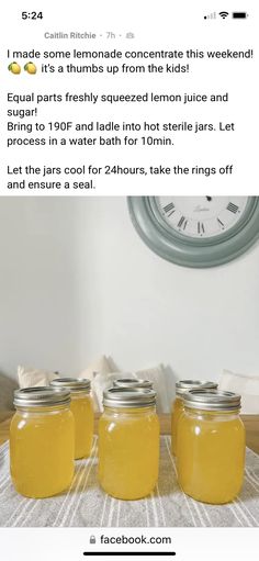 three jars filled with yellow liquid sitting on top of a table next to a clock