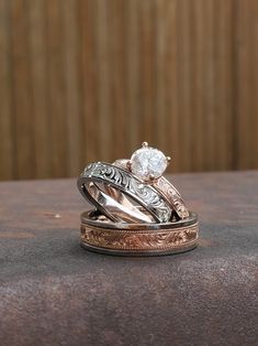 two wedding rings sitting on top of each other with one diamond in it's center