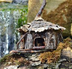 a birdhouse made out of wood and branches with moss growing on it's roof